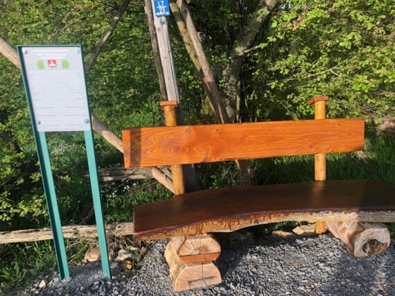 Hölzerne Sitzbank neben einem Hinweisschild